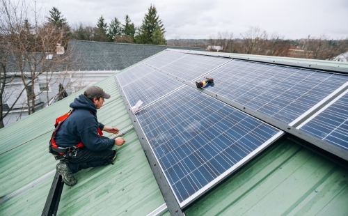 A worker installs solar panels on a roof 
